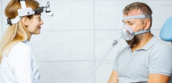 Adult man during a medical breathing treatment with respiratory mask against snoring sitting with doctor at the ENT office